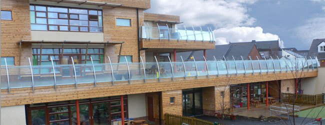 School elevation showing a long glass balustrade run on curved posts with brise soleil fins above the first floor glazing